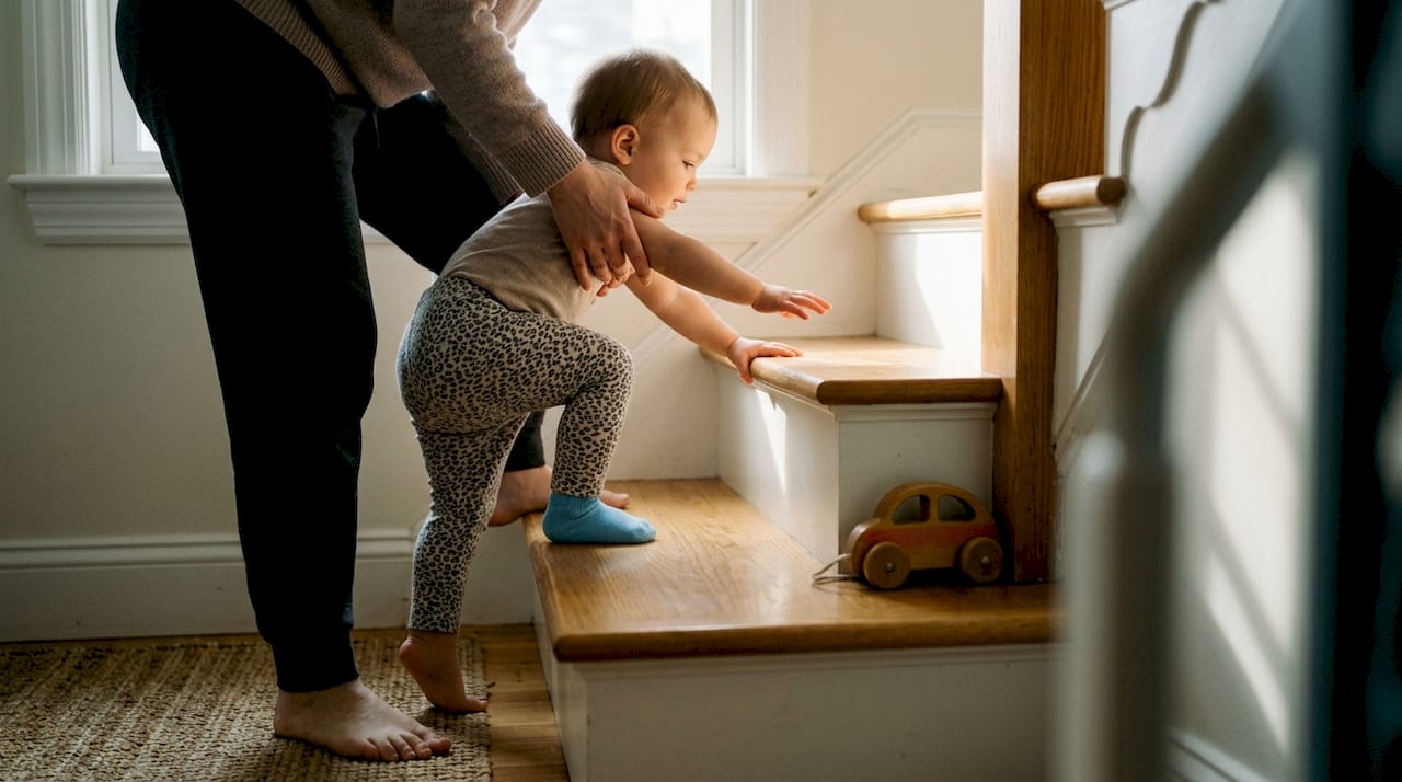 Parent guiding toddler on lower stairs