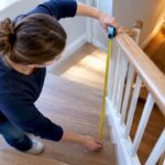 Hands measuring stair handrail height