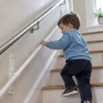 Toddler using KiddieRail on home stairs