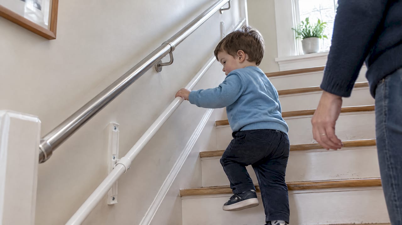 Toddler using KiddieRail on home stairs