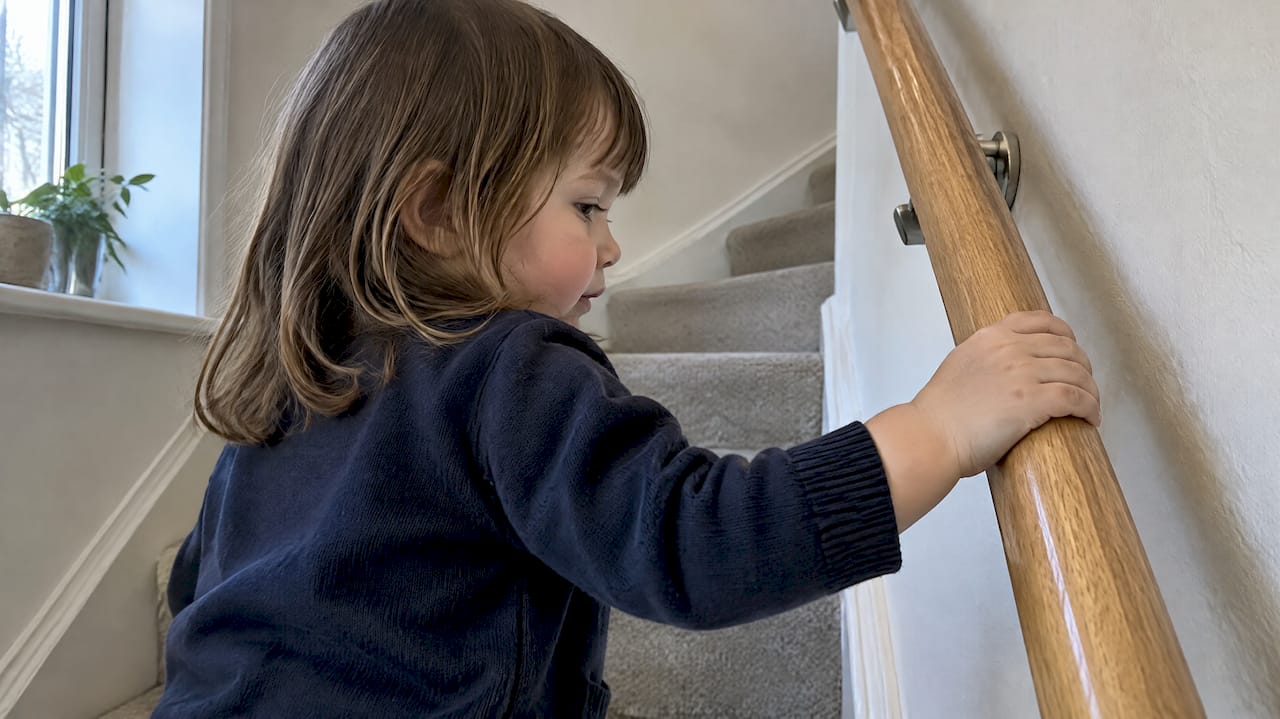 Small hand gripping a rounded wooden rail