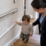 Toddler gripping a KiddieRail on stairs